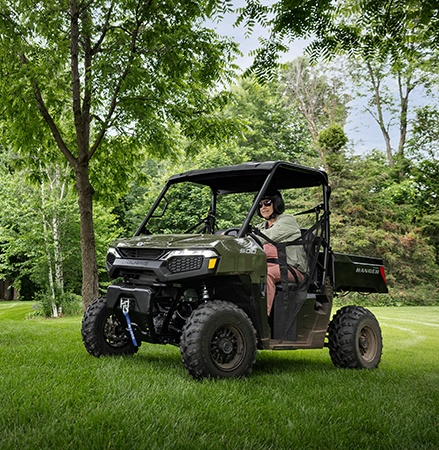 Un hombre en un UTV Polaris RANGER 500 2026 conduciendo por su jardín.
