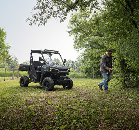 Un hombre usando el cabrestante desde la parte delantera de un UTV Polaris RANGER 500 2026.
