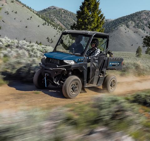 Deux personnes à bord d’un VUTT Polaris RANGER SP 570 2026 sur un sentier poussiéreux.