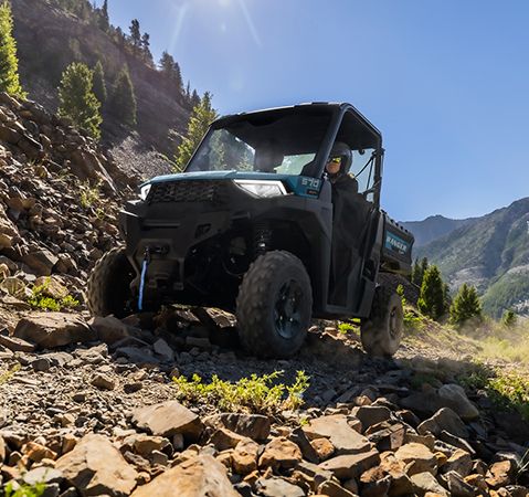 Deux personnes à bord d’un VUTT Polaris RANGER SP 570 2026 qui grimpe sur un terrain rocailleux avec une garde au sol inégalée de 27,9 cm (11 po).