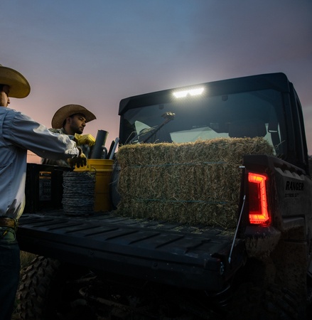 2 cowboys loading fencing gear into the cargo box of a 2026 Polaris RANGER XD 1500 NorthStar Edition extreme duty UTV at dusk.