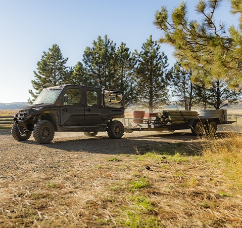 A 2026 Polaris RANGER XD 1500 NorthStar Edition extreme duty UTV pulling a heavy trailer fully loaded with fenceposts and other farm related items.