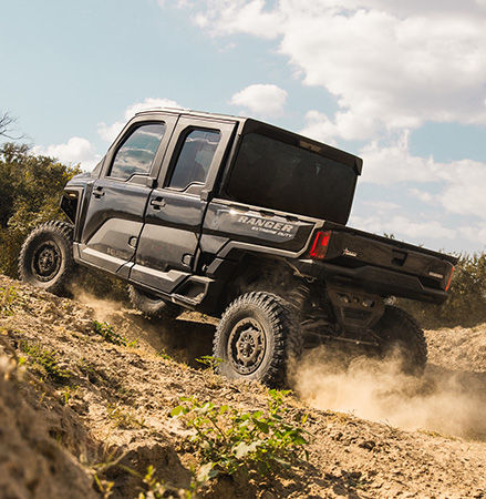 A 2026 Polaris RANGER CREW XD 1500 NorthStar Texas Edition extreme duty UTV climbing uphill showing the 16-inches of ground clearance.