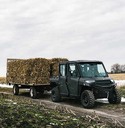 A 2026 Polaris RANGER CREW XP 1000 NorthStar Edition UTV pulling a trailer fully loaded with square bales. 