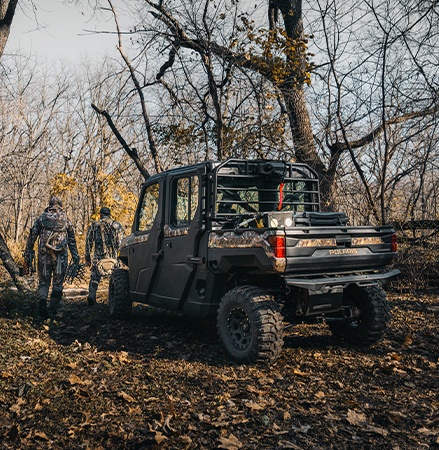 2 hunters walking away from a 2026 Polaris RANGER CREW XP 1000 NorthStar Edition UTV in the Polaris Pursuit Camo colorway.