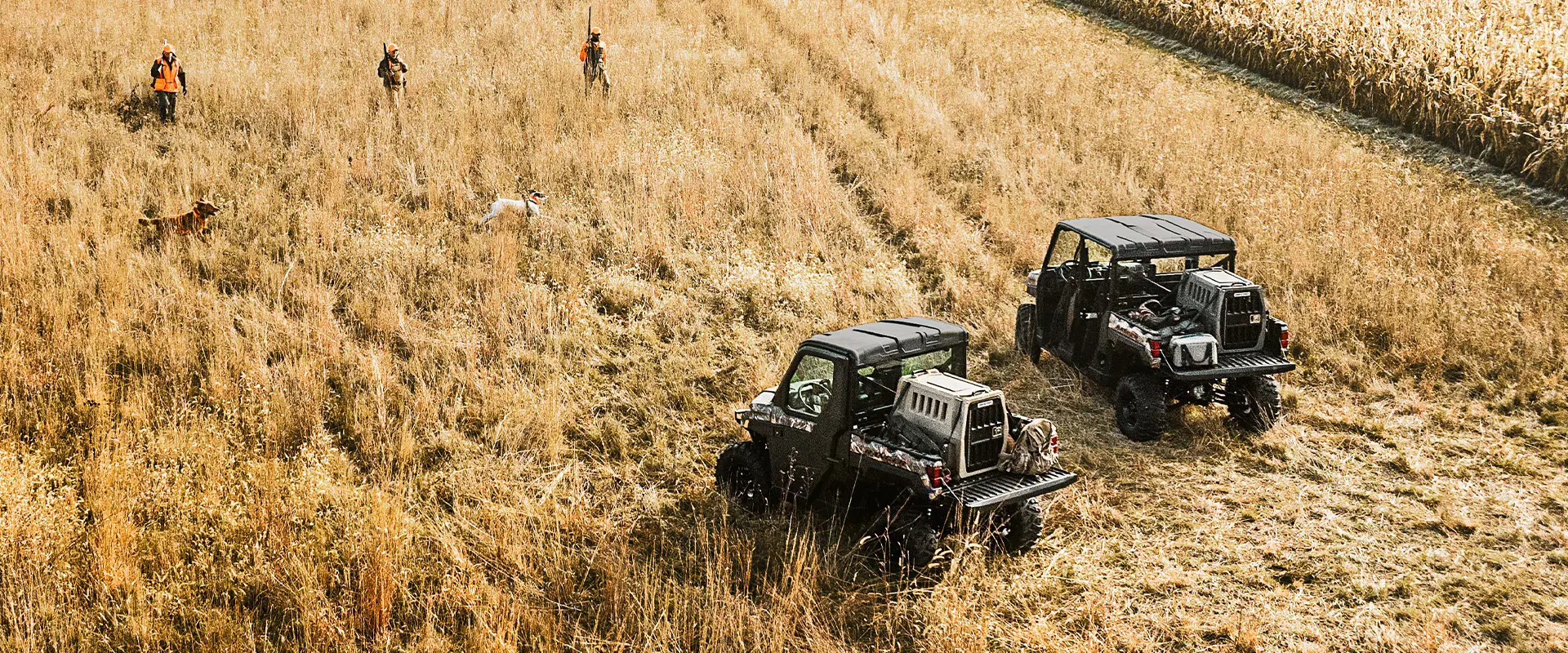 Hunters walking away from their 2026 Polaris RANGER XP 1000 NorthStar Edition utility vehicles in a field.