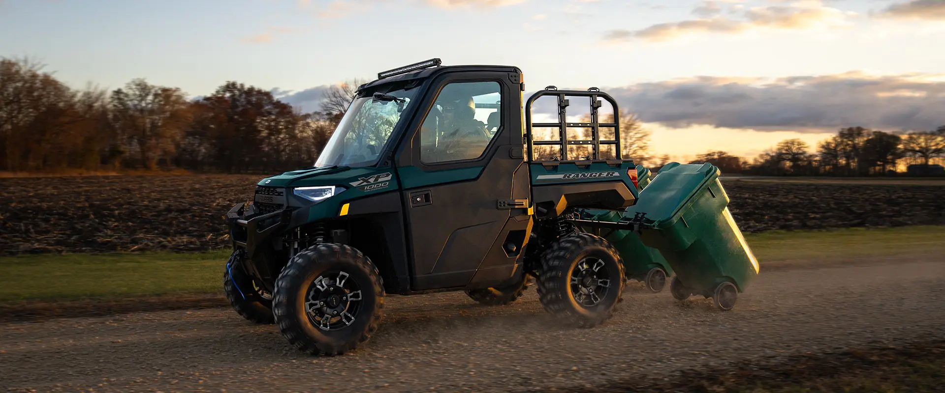 A 2026 Polaris RANGER XP 1000 NorthStar Edition utility vehicle pulling trashcans.