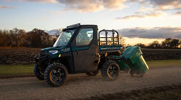A 2026 Polaris RANGER XP 1000 NorthStar Edition utility vehicle pulling trashcans.