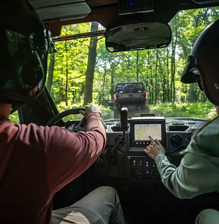 A rider in a 2026 Polaris RANGER XP 1000 NorthStar Trail Boss Edition UTV pointing to the RIDE COMMAND touch screen.