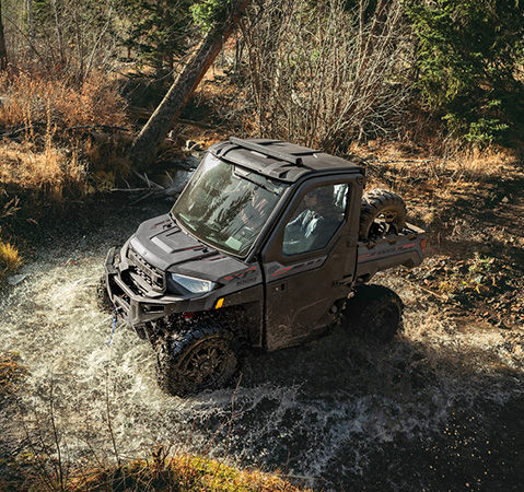 2 riders in the factory-installed cab system of a 2026 Polaris RANGER XP 1000 NorthStar Trail Boss Edition UTV.
