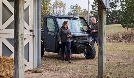 2 people leaving the cab of a 2027 Polaris RANGER 1000 CAB UTV.