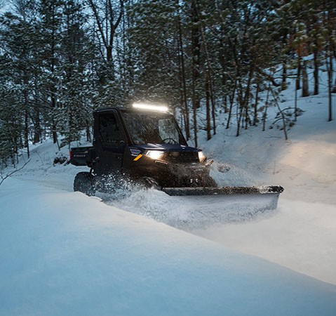 A person plowing snow with a 2027 Polaris RANGER 1000 CAB UTV.