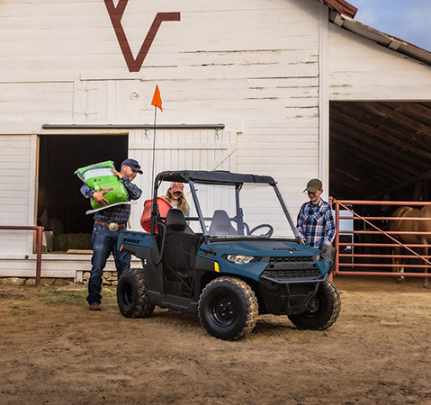 A man placing a 50lb bag in the cargo box of a 2027 Polaris RANGER 150 EFI youth UTV.