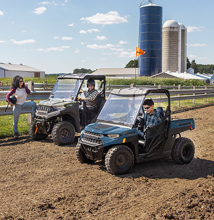 A kid adjusting the steering wheel on a 2027 Polaris RANGER 150 EFI youth UTV.