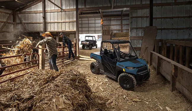 A kid in the barn with his 2027 Polaris RANGER 150 EFI youth UTV.