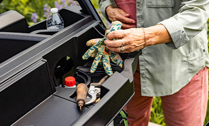 A woman grabbing gardening gloves from a storage area in her 2027 Polaris RANGER 500 UTV.