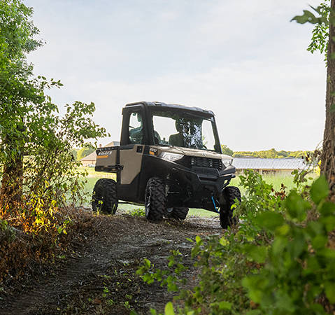 2 riders in a 2027 Polaris RANGER 600 NorthStar UTV taking a corner onto a forest trail.