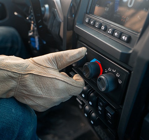 Gloved hand turning on the heat inside a 2027 Polaris RANGER XD 1500 NorthStar Extreme Duty UTV.