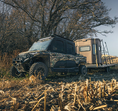 A 2027 Polaris RANGER CREW XD 1500 NorthStar Extreme Duty UTV pulling a trailer with a deer stand on it.