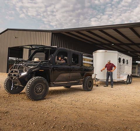 Una persona que está acoplando un remolque al enganche trasero del UTV Polaris RANGER XD 1500 NorthStar Texas Edition Extreme Duty 2027.