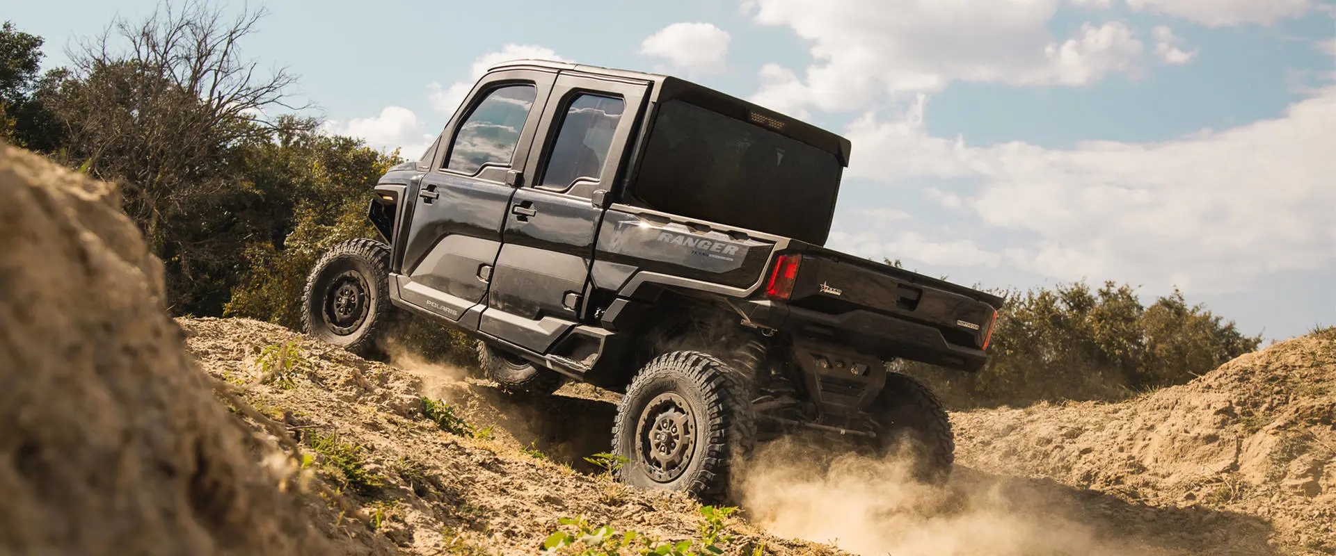 Un UTV Polaris RANGER CREW XD 1500 NorthStar Texas Edition para uso extremo 2027 subiendo una cuesta.