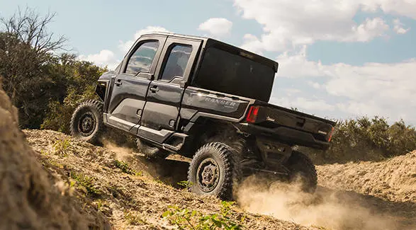 Un UTV Polaris RANGER CREW XD 1500 NorthStar Texas Edition para uso extremo 2027 subiendo una cuesta.