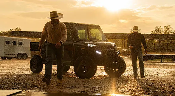 Dos agricultores bajo la lluvia mientras se alejan de un UTV Polaris RANGER CREW XD 1500 NorthStar Texas Edition 2027 para uso extremo.