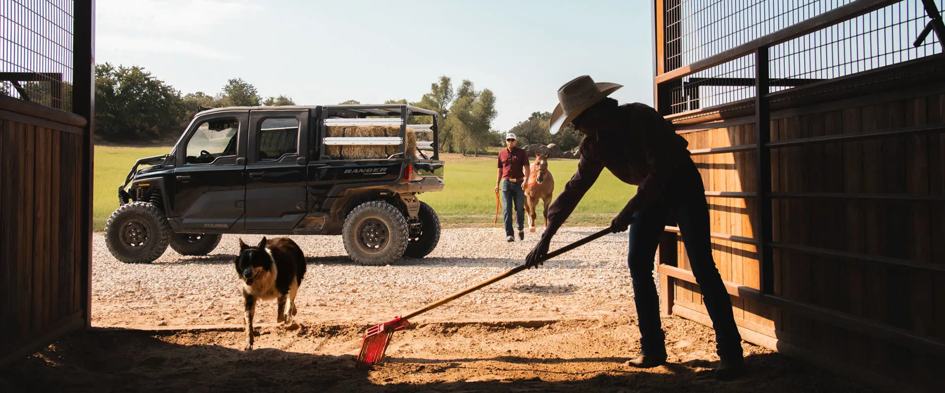 Un agricultor limpiando un granero con un UTV Polaris RANGER CREW XD 1500 NorthStar Texas Edition 2027 para uso extremo al fondo.