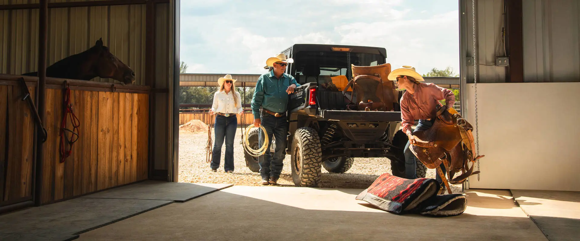 Tres personas cargando equipo para montar a caballo en la caja de carga de un UTV Polaris RANGER CREW XD 1500 NorthStar Texas Edition 2027 de uso extremo.