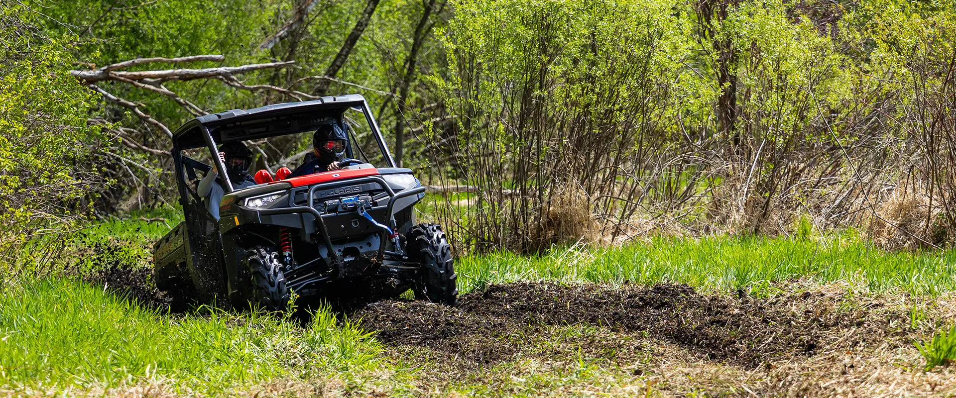 A 2027 Polaris RANGER XP 1000 Mud Edition UTV climbing out of some deep mud.