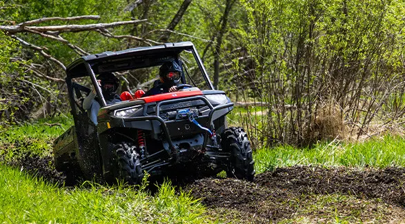 A 2027 Polaris RANGER XP 1000 Mud Edition UTV climbing out of some deep mud.