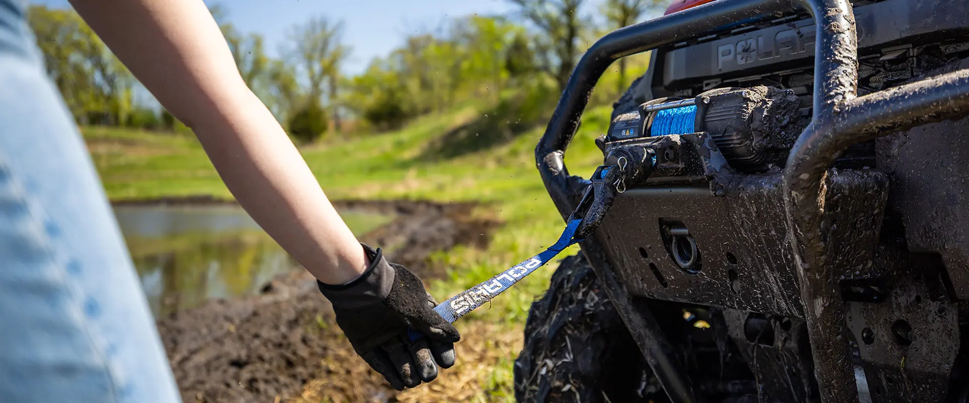 A person pulling out the winch on a 2027 Polaris RANGER XP 1000 Mud Edition UTV.