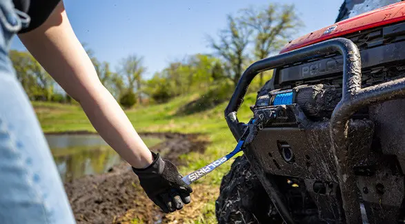 A person pulling out the winch on a 2027 Polaris RANGER XP 1000 Mud Edition UTV.
