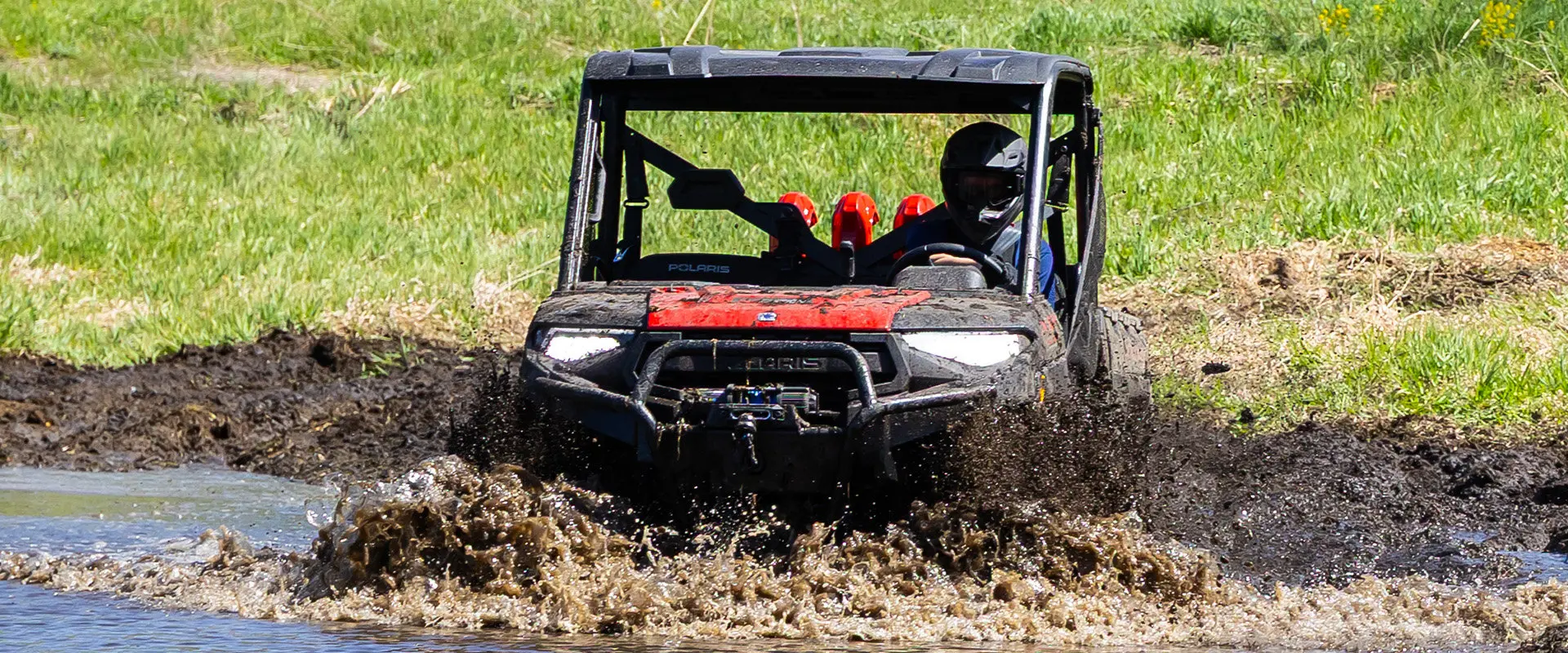 A 2027 Polaris RANGER XP 1000 Mud Edition UTV driving through some deep mud.