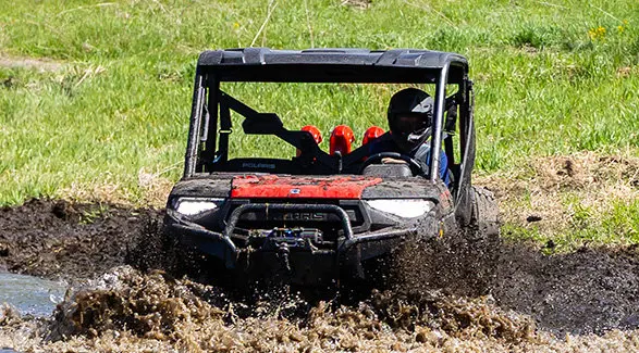 A 2027 Polaris RANGER XP 1000 Mud Edition UTV driving through some deep mud.