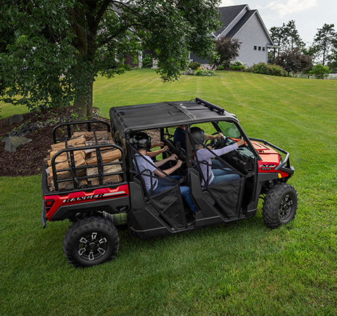 4 people in a 2027 Polaris RANGER XP 1000 UTV driving on a lush lawn.