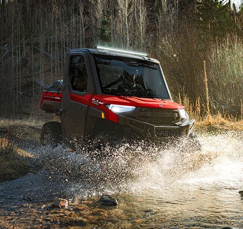 A 2027 Polaris RANGER XP 1000 NorthStar enclosed UTV driving through a ravine.
