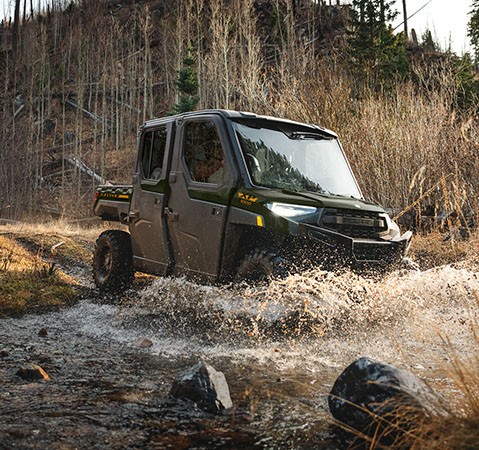 A 2027 Polaris RANGER CREW XP 1000 NorthStar enclosed UTV driving through a river.