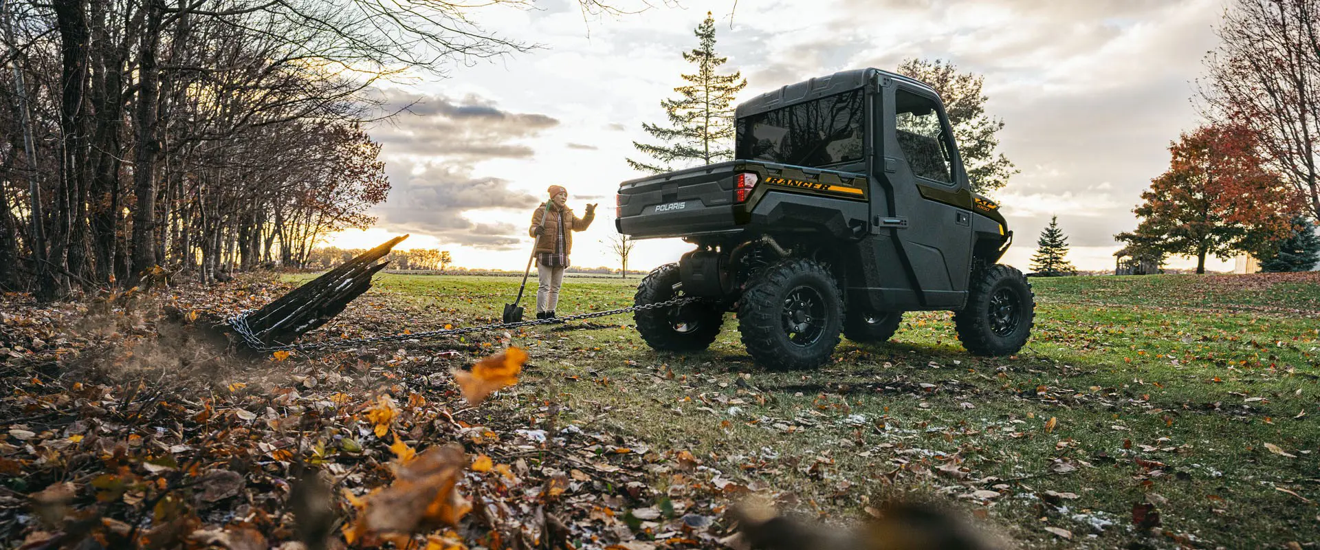 A 2027 Polaris RANGER XP 1000 NorthStar enclosed UTV pulling out a stump with a chain attached to the rear hitch.