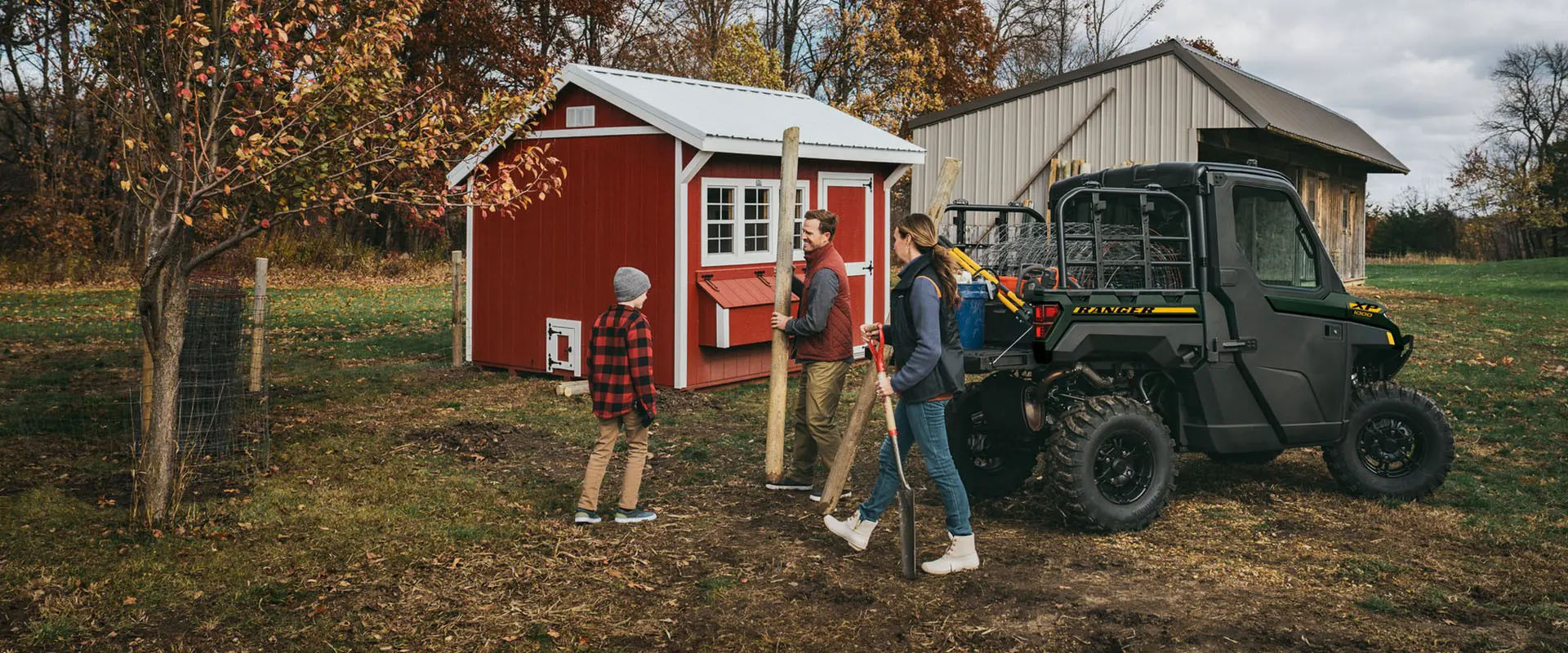 A family using their 2027 Polaris RANGER XP 1000 NorthStar enclosed UTV to haul fence posts and fence.