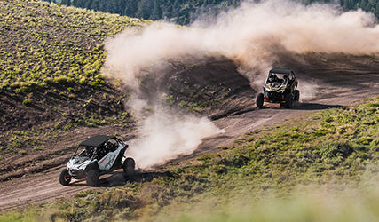 Two RZR Pro XP vehicles racing on a green field