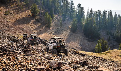 a group of RZRs going through a rocky trail