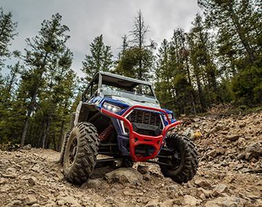 Polaris RZR Trail racing on a trail road in the sunset