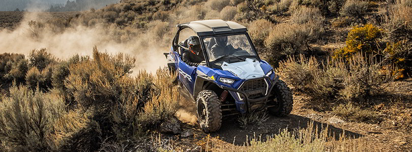 Polaris RZR Trail  racing on a trail road in the sunset