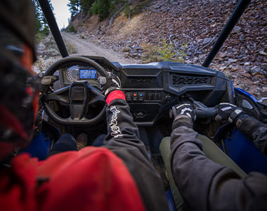 Polaris RZR Trail racing on a trail road in the sunset