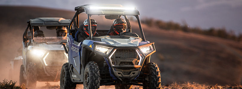 Polaris RZR Trail racing on a trail road in the sunset