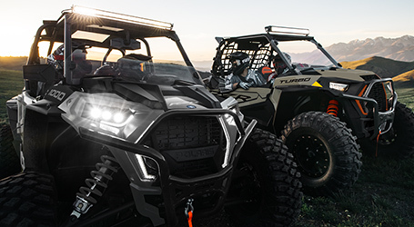 Front view of two RZRs parked with their frontal lights on