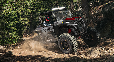 RZR going up a hill through the forest