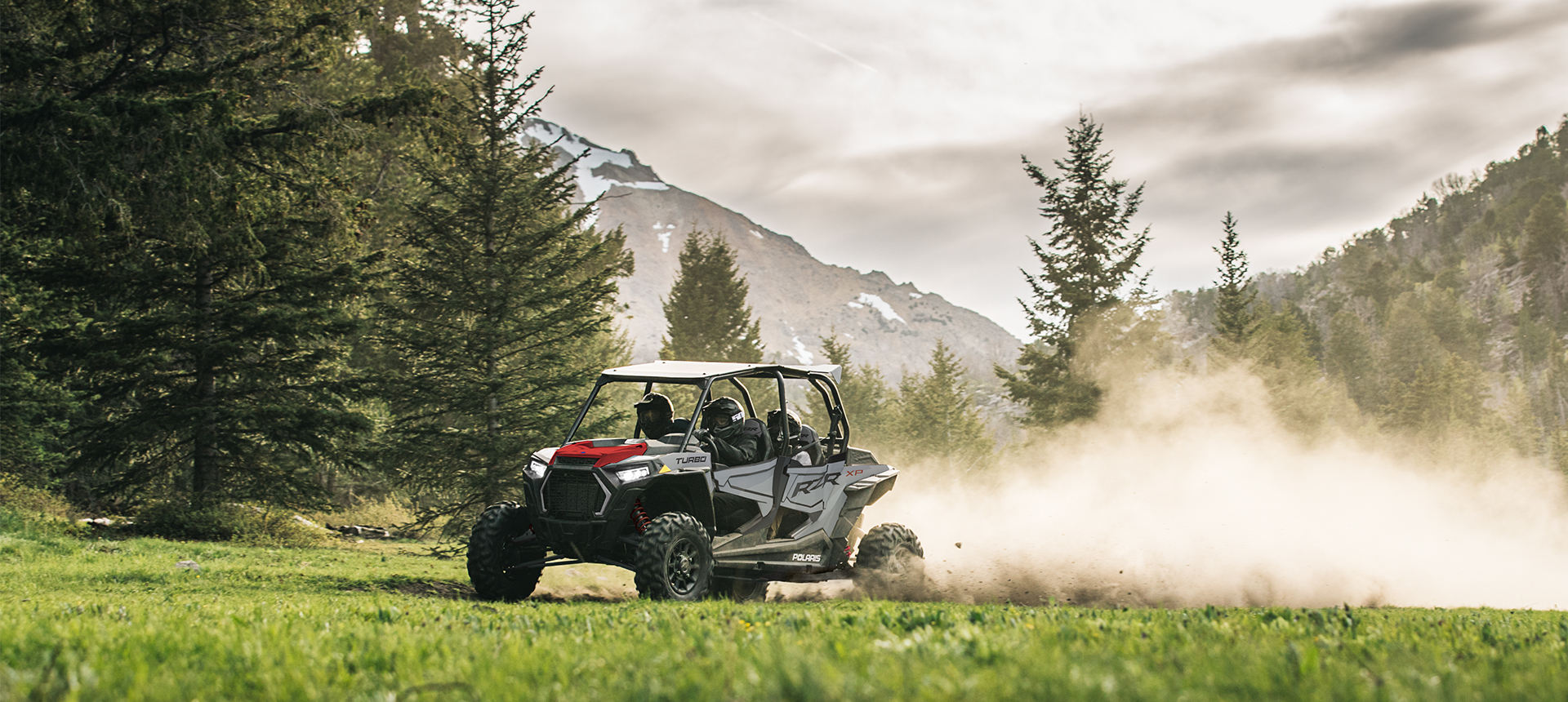 RZR XP 4 Turbo racing through a green field