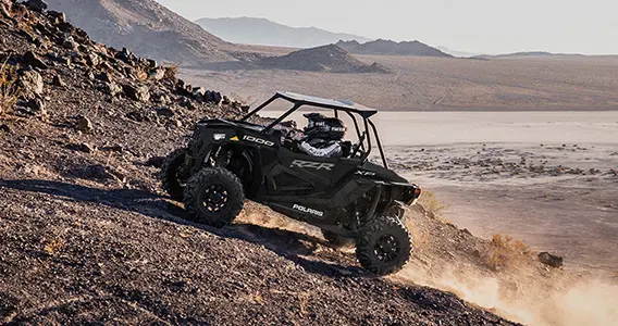 2 riders climbing a hill in a rzr pro xp 1000 side by side